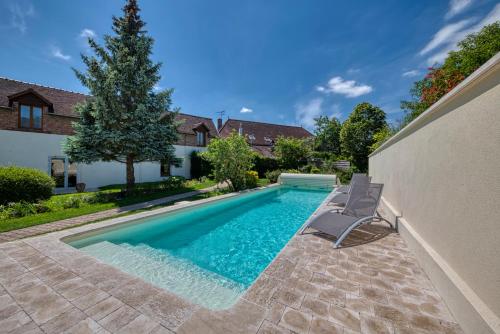 einen Pool mit zwei Stühlen neben einem Haus in der Unterkunft Auberge du Lac Hôtel & Spa Restaurant Gastronomique in Mesnil-Saint-Père