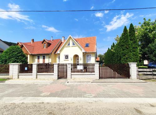 une maison blanche avec une clôture et un portail dans l'établissement Apollo Vendégház, à Bogács