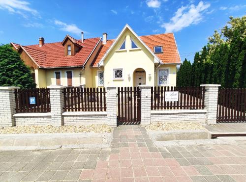 une maison avec une clôture et un toit rouge dans l'établissement Apollo Vendégház, à Bogács