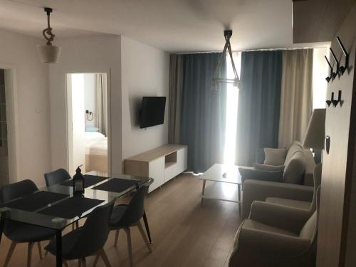 ein Wohnzimmer mit einem Sofa, einem Tisch und Stühlen in der Unterkunft Nadmorskie Tarasy Apartament 312 in Kołobrzeg