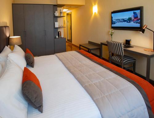 een groot bed in een hotelkamer met een televisie bij Hotel Grand Brizo Buenos Aires in Buenos Aires