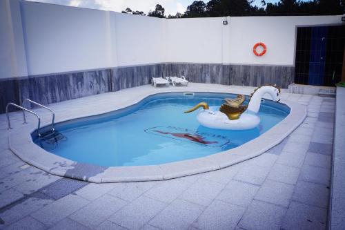 a swimming pool with a swan in the middle at Casinha das Bonecas - Casa com Piscina Privada in Aveiro