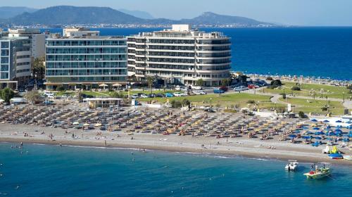 een strand met parasols en mensen op het strand bij Cactus Hotel in Rhodos-stad