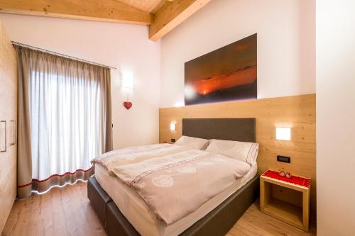 um quarto com uma cama grande e uma pintura na parede em Cèsa Baissa em Campitello di Fassa