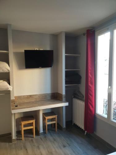 Cette chambre dispose d'un bureau et d'une télévision murale. dans l'établissement Hôtel Belfort, à Montreuil