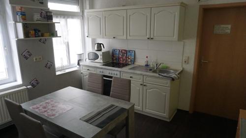 a kitchen with white cabinets and a table and a sink at Hostel im Medizinerviertel in Halle an der Saale