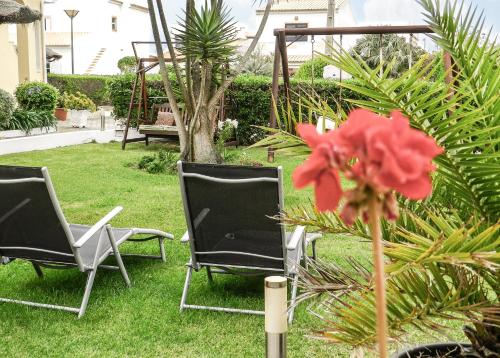 dos sillas y una flor roja en un patio en Residencia Julio, en Sagres