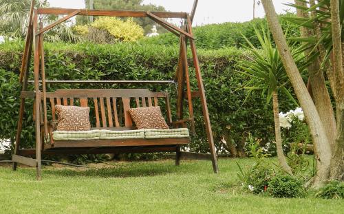 Un columpio de madera con almohadas sentadas en el césped en Residencia Julio, en Sagres