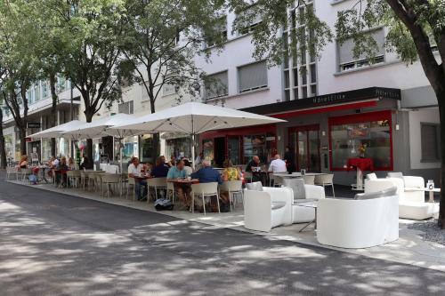 een groep mensen die buiten een restaurant aan tafel zitten bij Hôtel Elite in Sion