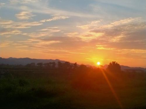 um pôr-do-sol com o pôr-do-sol sobre um campo em Samerdrow Khao Yai em Mu Si