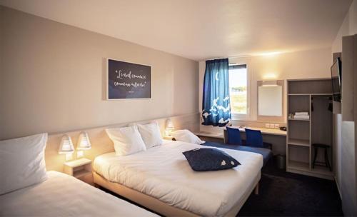 a hotel room with two beds and a window at Ace Hôtel Toulouse Blagnac in Cornebarrieu