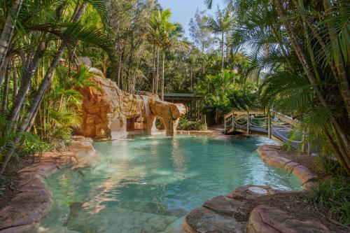 a pool in the middle of a resort with palm trees at BreakFree Aanuka Beach Resort in Coffs Harbour