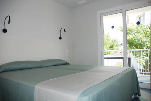 a white bedroom with a bed and a large window at Apartamentos Sunway Arizona in Sitges