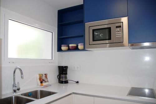 a kitchen with a microwave oven above a sink at Apartamentos Sunway Arizona in Sitges