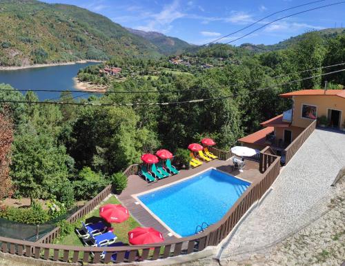 une maison avec une piscine entourée de parasols dans l'établissement Casa Encosta do Gerês-Ferias no Gerês, à Vieira do Minho