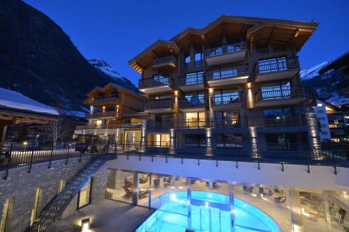 a hotel with a swimming pool in front of a building at Alpenhotel Fleurs de Zermatt in Zermatt