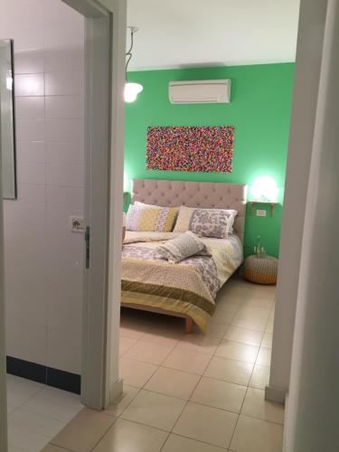 1 dormitorio con cama y pared verde en Intra Rooms, en Olbia