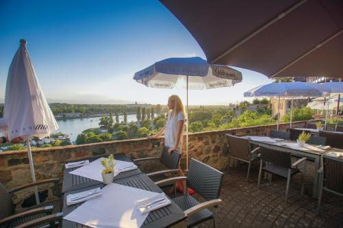 une femme debout sur le balcon d'un restaurant avec des tables et des parasols dans l'établissement Hotel Stadt Breisach, à Vieux-Brisach