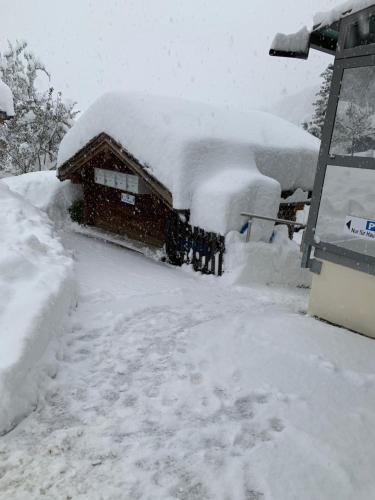 dom pokryty śniegiem obok budynku w obiekcie Hotel Haus Mühlebach w mieście Ernen