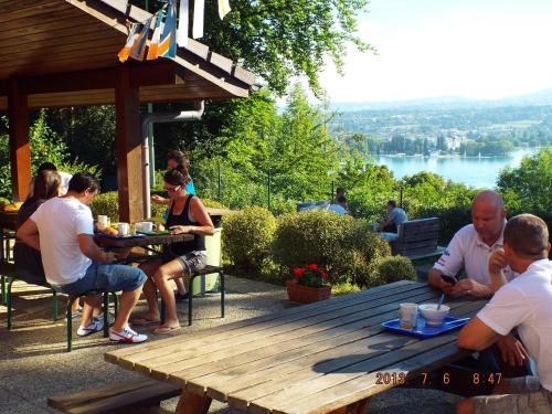 een groep mensen die rond een houten picknicktafel zitten bij Auberge de Jeunesse HI Annecy in Annecy