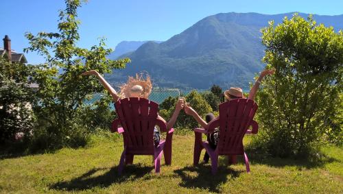 twee mensen zitten in stoelen in een veld met bergen op de achtergrond bij Auberge de Jeunesse HI Annecy in Annecy