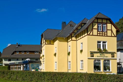 een geel huis met een zwart dak bij Land-gut-Hotel Cafe Meier in Kurort Oybin