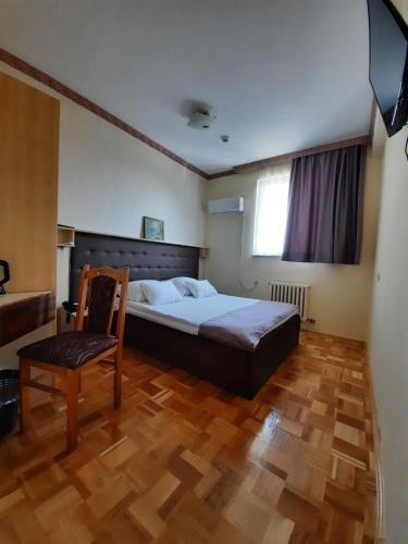 um quarto com uma cama, uma cadeira e uma televisão em Hotel & Restaurant Great Wall - Airport em Saraievo