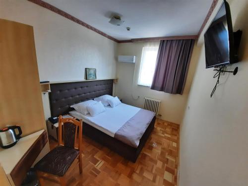 um quarto com uma cama, uma televisão e uma cadeira em Hotel & Restaurant Great Wall - Airport em Saraievo