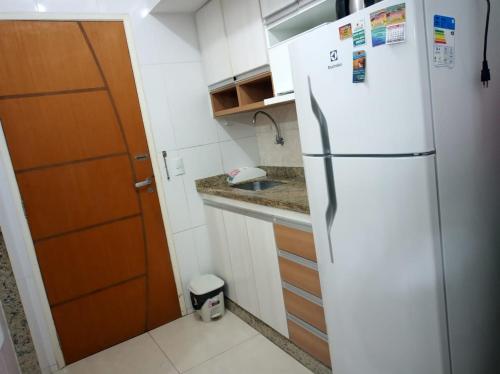 a kitchen with a white refrigerator and a sink at Cond. Hotel Âncora em frente Praia do Peró in Cabo Frio