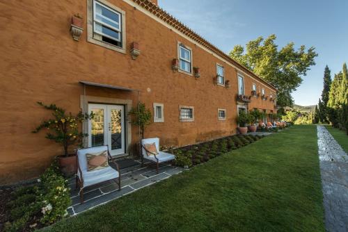 een bakstenen gebouw met twee stoelen in een tuin bij Quinta do Vallado - Douro Wine Hotel in Peso da Régua