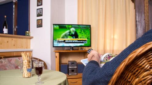 une personne assise à une table qui regarde une télévision dans l'établissement Ferienwohnung KraftTanken, à Hallstatt