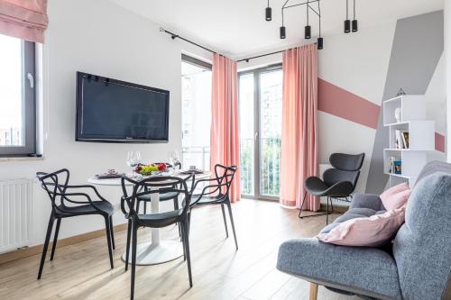 een woonkamer met een tafel en stoelen en een televisie bij Apartament Old Town Nest in Gdańsk