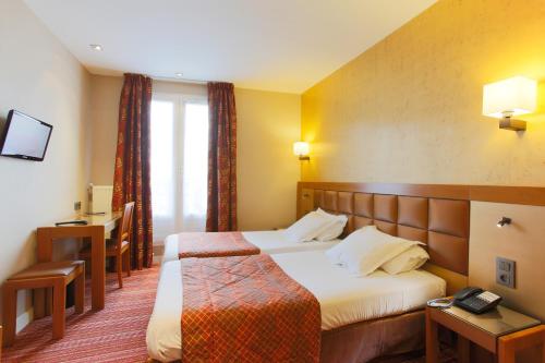 a hotel room with a bed and a desk and a window at Hotel Bellevue Saint-Lazare in Paris