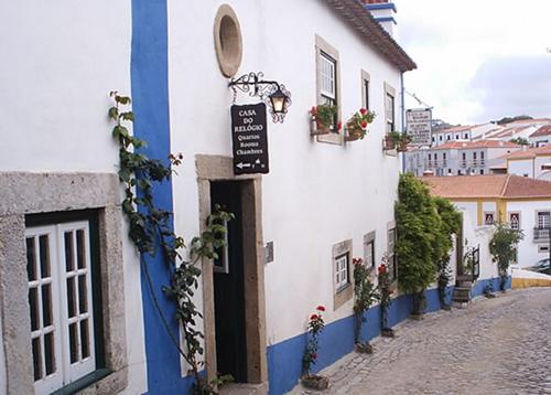 un bâtiment blanc et bleu avec un panneau sur celui-ci dans l'établissement Casa Do Relogio, à Óbidos