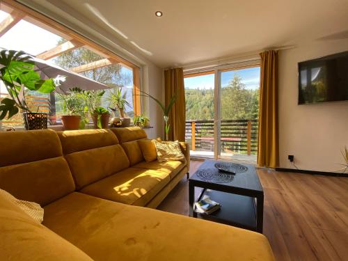 sala de estar con sofá amarillo y ventana grande en Apartamenty i Las, en Brenna