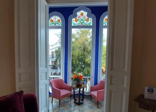 Cette chambre dispose de 3 fenêtres, d'une table et de chaises. dans l'établissement Hotel Noucentista, à Sitges