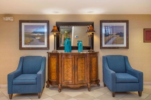 a room with two blue chairs and a table and a mirror at Clarion Collection Hotel Arlington Court Suites in Arlington