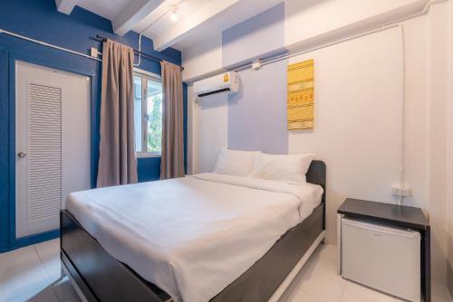 a small bedroom with a white bed and a window at BEDGASM Hotel x Cafe Nimman in Chiang Mai