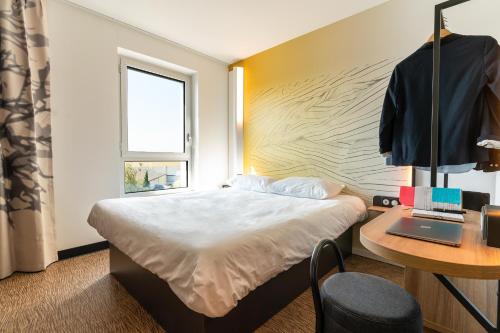 una camera con letto e scrivania con computer portatile di B&B HOTEL Poitiers Aéroport a Poitiers