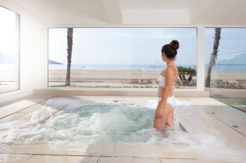 Eine Frau steht in einem Whirlpool mit Meerblick in der Unterkunft Hotel Montecarlo Spa & Wellness in Roses