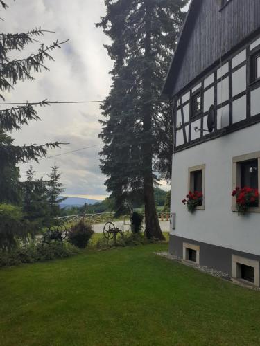 a white house with flowers in a yard at Agroturystyka Łysa Góra in Jelenia Góra