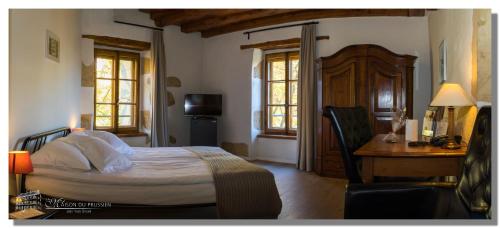 a bedroom with a bed and a desk and windows at Hôtel La Maison du Prussien in Neuchâtel