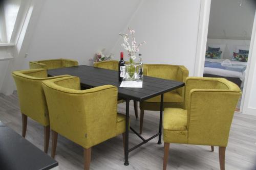 a dining room table with yellow chairs and a bottle of wine at The Riverside Logies & Restaurant in Maarssen