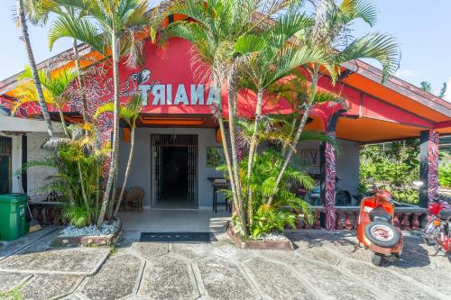 a restaurant with palm trees in front of it at OYO 2527 Hotel Triana in Palangkaraya