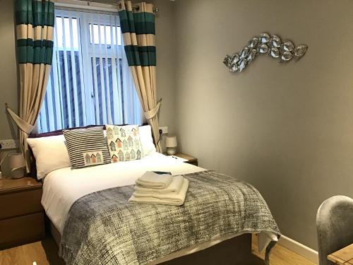 - une chambre avec un lit, une couverture et une fenêtre dans l'établissement Coast 77 B&B, à Poole