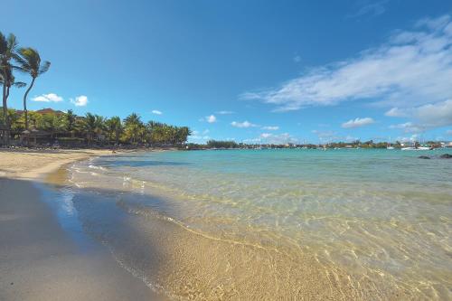 a sandy beach with palm trees and the ocean at Mauricia Beachcomber Resort & Spa in Grand Baie