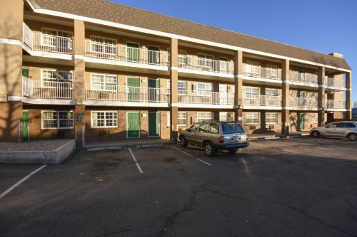 a car parked in a parking lot in front of a building at HomeTowne Studios by Red Roof Denver - Lakewood West in Lakewood