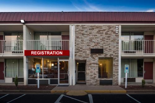 un bâtiment avec un panneau d'immatriculation rouge devant lui dans l'établissement Red Roof Inn Dumfries-Quantico, à Dumfries