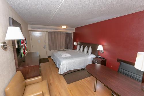 ein Hotelzimmer mit einem Bett und roten Wänden in der Unterkunft Red Roof Inn PLUS+ Washington DC - Alexandria in Alexandria