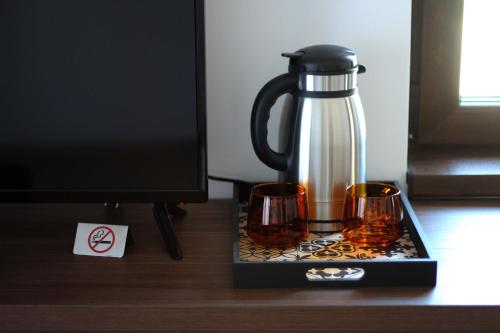 eine Kaffeemaschine und zwei Gläser auf einem Schreibtisch neben einem Computermonitor in der Unterkunft Pensiunea Casa Iorgovanul Urseni in Timişoara